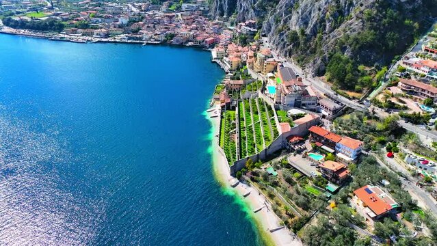 Aerial Forward Shot Of Houses And Vehicles In Town By Lake Garda Near Mountain On Sunny Day - Limone sul Garda, Italy