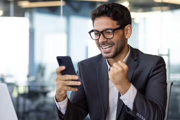 Close-up portrait of successful businessman, winner holding phone, man celebrating good results...
