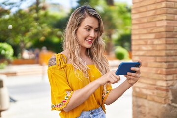 Young woman smiling confident watching video on smartphone at street