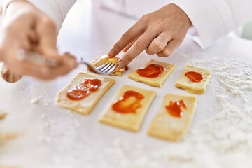 Young woman wearing cook uniform cooking pasta at kitchen