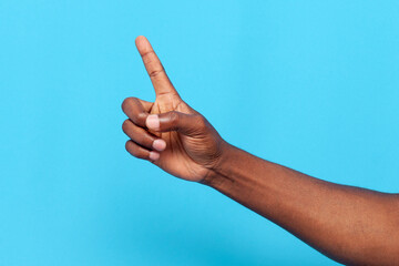 african american male hand pointing finger at copy space on blue isolated background, hand showing index finger