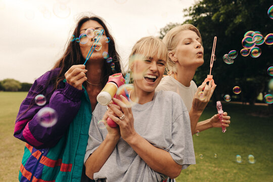Group of female friends playing with bubbles in a park