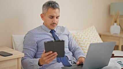 Young hispanic man business worker using laptop and touchpad at hotel room