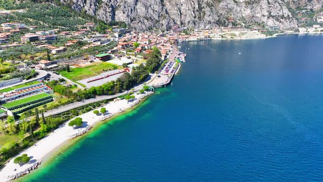Aerial Panning Shot Of Houses Near Lake Garda And Mountain Ranges, Drone Flying Over Town On Sunny Day - Limone sul Garda, Italy