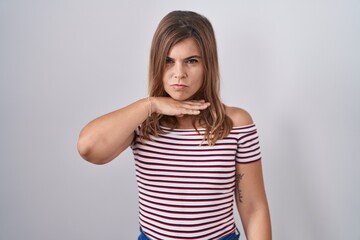 Obraz premium Young hispanic woman standing over isolated background cutting throat with hand as knife, threaten aggression with furious violence