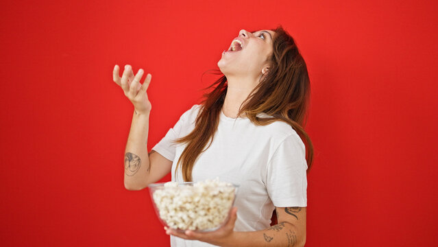 Young beautiful hispanic woman eating popcorn laughing a lot over isolated red background