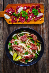 Pho soup - Vietnamese soup with beef on wooden table
