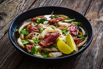 Pho soup - Vietnamese soup with beef on wooden table
