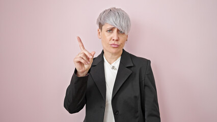 Young woman business worker saying no with finger over isolated pink background