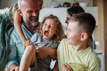 Cheerful family with three kids laughing and having fun together.