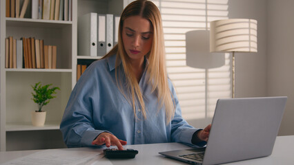 Confused puzzled Caucasian girl woman at office counting money business finance with calculator and laptop banking app failure with documents bills mistake businesswoman count taxes financial problems