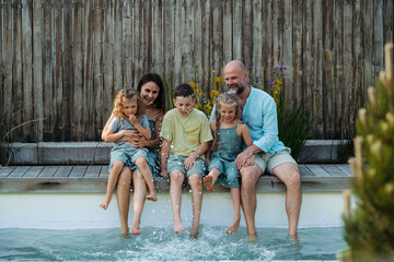 Fototapeta na wymiar Cheerful family with three kids having fun together sitting by a pool.