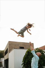 Father throwing little daugter up in the air.