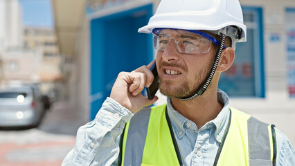 Young caucasian man architect talking on smartphone at construction place