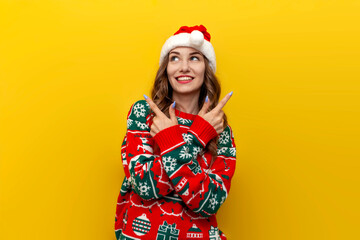 unsure girl in christmas sweater and santa claus hat chooses from two options on yellow isolated...