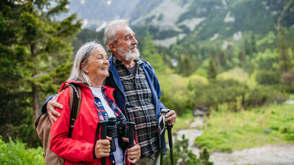 Active senior couple hiking together in autumn mountains.