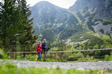 Fototapeta na wymiar Active senior couple hiking together in autumn mountains.