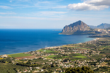A wide view from Erice in Sicily down to the blue sea, beach, villages, green fields and Monte Cofano.