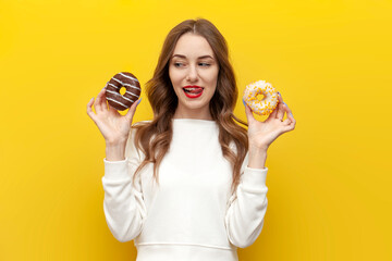 young cute girl with sweet donuts thinks and chooses on yellow isolated background, woman with pastry imagines