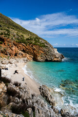 Fototapeta na wymiar A secluded bay with white sand and turquoise waters in the Mediterranean Sea between the rocks of the Zingaro National Park in Sicily in the sun