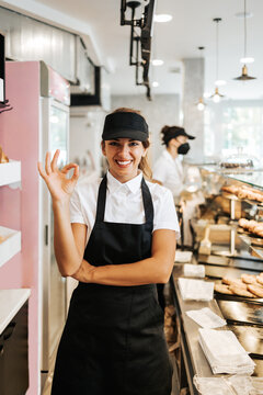 Beautiful young and happy female worker working in a modern bakery or fast food restaurant.