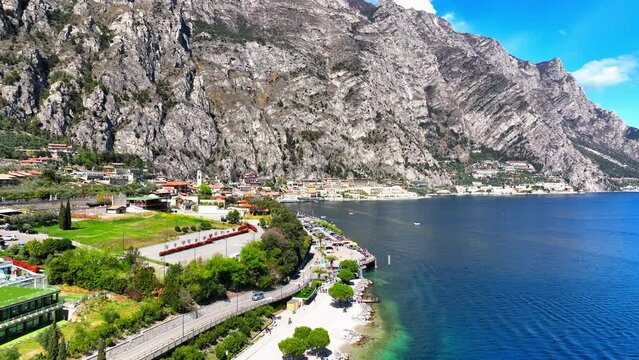 Aerial Forward Shot Of People By Houses Near Lake Garda And Mountains On Sunny Day - Limone sul Garda, Italy