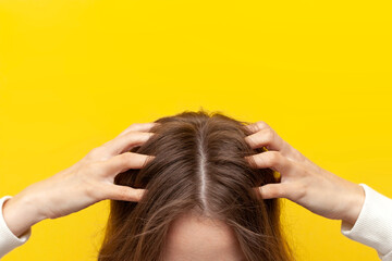 girl scratches her hair and head with her hands for dandruff and skin problems, close-up of the head
