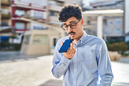 Young caucasian man talking on the smartphone with serious expression at street