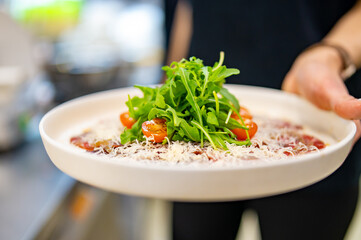 woman chef hands cooking carpaccio with arugula and cheese on kitchen