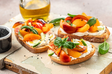 Toast, snack, bruschetta, sandwich with cream cheese, peaches, tomatoes and green basil leaves, Concept healthy and balanced eating. place for text, top view