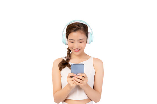 Beautiful Young Asian Woman wearing wireless headphones and listening to music and using phone Young Asian teen lady using smart phone for listening music in headphones isolated on white background