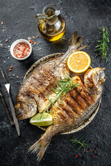 delicious grilled dorado or sea bream fish with lemon. vertical image. top view. place for text