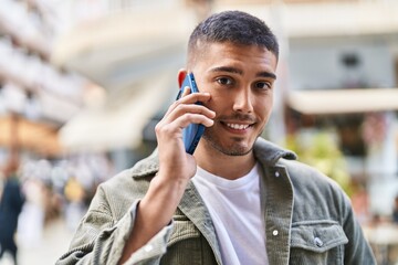 Young hispanic man smiling confident talking on the smartphone at street