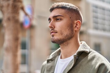 Young hispanic man with relaxed expression standing at street