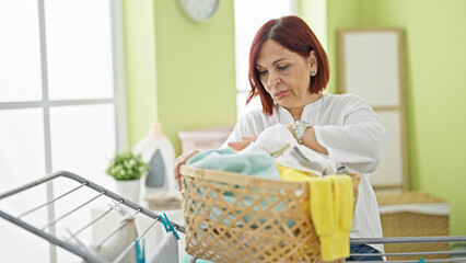 Middle age woman looking for clothes on basket at laundry room
