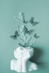 A figurine of a head with butterflies on a colored background. Mental health concept