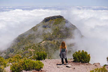 Travelling and exploring Madeira island landscapes and famous places. Young female tourist enjoying spectacular Pico Ruivo outdoor view. Summer tourism by Atlantic ocean and mountains. 