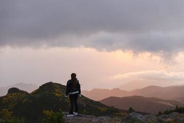 Travelling and exploring Madeira island landscapes and travel destinations. Young female tourist enjoying the sunrise and outdoor spectacular scenery. Summer tourism by Atlantic  ocean and mountains.