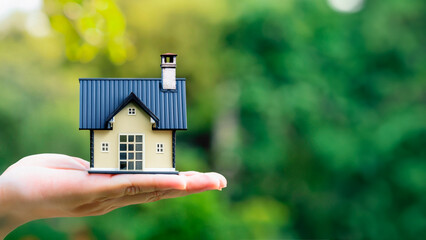 Hand holding a miniature of a beautiful house with doors and windows, civil construction, housing.