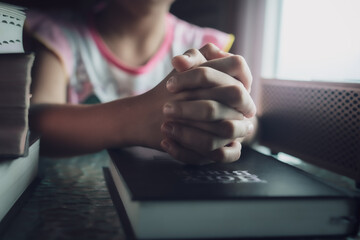 Hands of child girl praying on bible with pray with faith, christian concept.