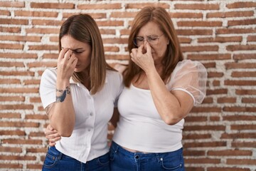 Hispanic mother and daughter wearing casual white t shirt tired rubbing nose and eyes feeling fatigue and headache. stress and frustration concept.
