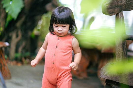 Portrait photo of white little girl with black hair is wearing orange suit in cutety action. People portrait photo with facing focus.