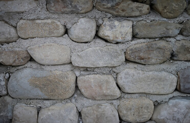 Neatly stacked rough cut stone wall seamless texture background. Old stone building from stones concept