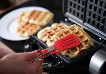 Belgian waffle dessert in waffle iron closeup. Making waffles at home