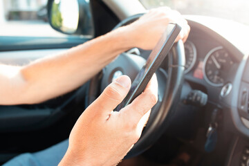 Hands of man driver using mobile phone while driving. Road danger concept