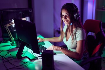 Young beautiful hispanic woman streamer playing video game using computer at gaming room