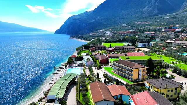 Aerial Forward Shot Of Houses In Town Amidst Lake And Mountain Ranges On Sunny Day - Limone sul Garda, Italy