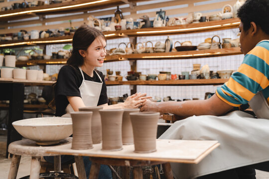 The potter's hands are gently and surely formed by a clay pot on a potter's wheel. The master potter works in a workshop, Woman hands working on pottery wheel making a clay pot, raw clay shaping