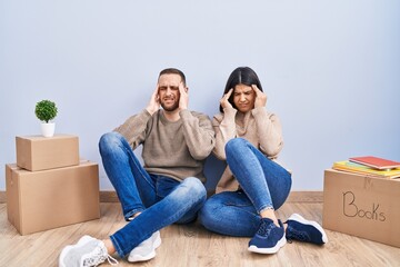 Young couple moving to a new home with hand on head, headache because stress. suffering migraine.