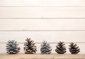 Decorative pine cones on a wooden board with a white wooden background